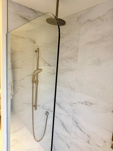 a shower in a bathroom with white marble walls at Fully furnished cozy home in Montréal