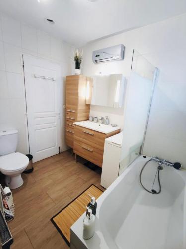 une salle de bain avec une baignoire, un lavabo et des toilettes dans l'établissement Logement entier avec coin jardin, à Baillargues