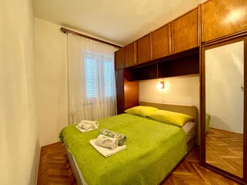 a small bedroom with a green bed and a mirror at Villa Millefiori - Apartments Mali Lošinj in Mali Lošinj