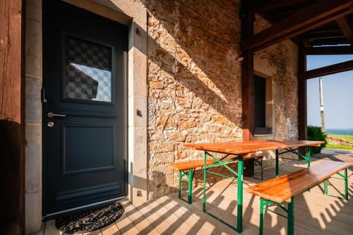 un porche avec une porte, une table et des bancs dans l'établissement Gîte de la Chassagne pour 4 à 5 personnes, à Fontain