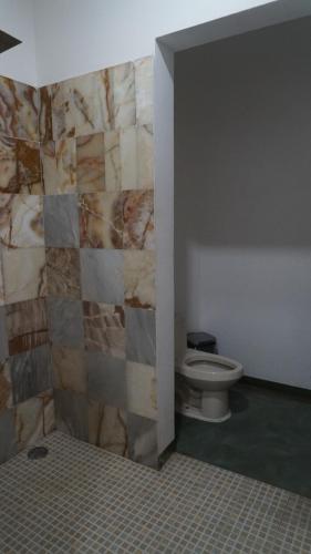 a bathroom with a toilet and a stone wall at Madre Tierra Hostal in Puerto Escondido