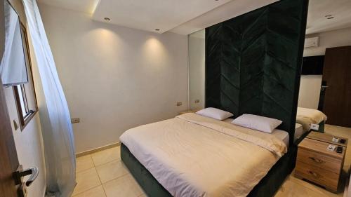 a bedroom with a bed with a green headboard at Bright and Cosy appartment in Oulad Yakoub
