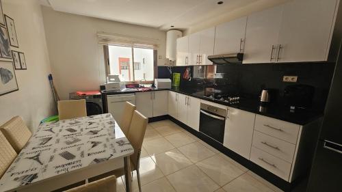 a kitchen with white cabinets and a table with chairs at Bright and Cosy appartment in Oulad Yakoub