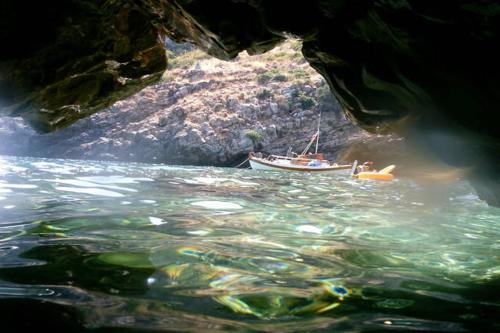 a boat in the water next to a cave at villapetramarina in Tsakaíoi