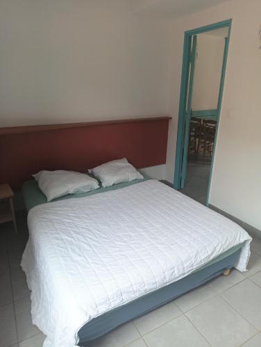 Cette chambre comprend un grand lit avec des draps blancs et un miroir. dans l'établissement Maisonnette Bleu Piscine, à Argelès-sur-Mer