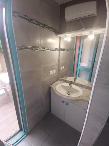 une salle de bain avec un lavabo et un miroir dans l'établissement Maisonnette Bleu Piscine, à Argelès-sur-Mer