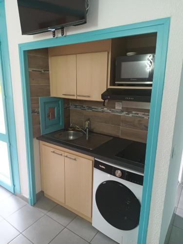 une cuisine avec un évier et un micro-ondes dans l'établissement Maisonnette Bleu Piscine, à Argelès-sur-Mer
