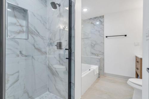 a white bathroom with a shower and a toilet at Sleeps 24-spacious Suites Near Fq W Pool in New Orleans
