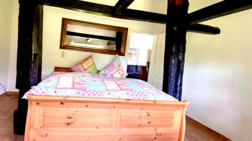 a bedroom with a wooden bed and a mirror at Altes Landhaus Oste, Appartement- Hotel mit Kamin in Hemmoor