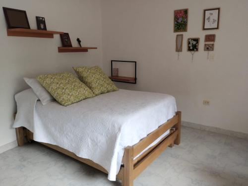 a bedroom with a bed with white sheets and pillows at Central, mejor clima, campestre en Calambeo, a 5 minutos de la vida cultural in Ibagué