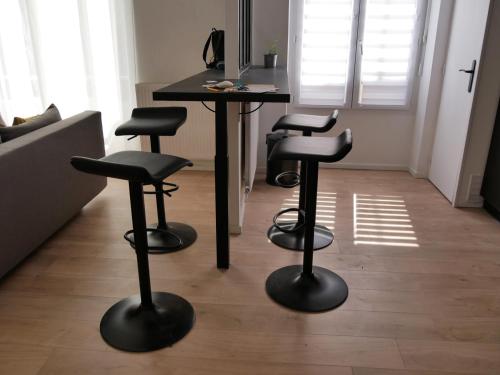 une chambre avec trois tabourets de bar et une table dans l'établissement Joli T2 proche Arènes et gare, à Nîmes