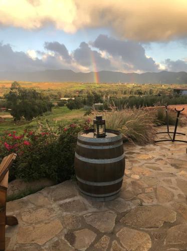 a barrel sitting on the ground with a rainbow in the background at En'kanto Valle de Guadalupe in San Marcos