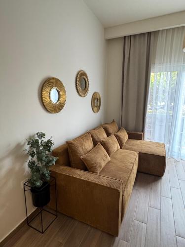 a living room with a brown couch and two mirrors at Artemis Apartments in Diakopto