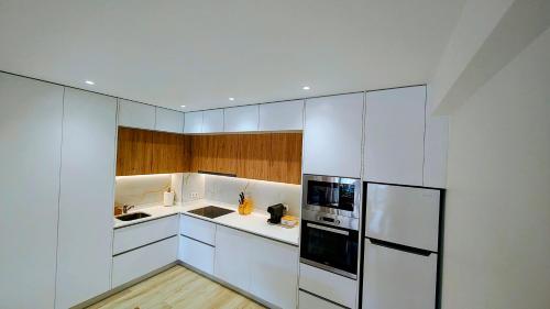 a kitchen with white cabinets and a refrigerator at Pedra do Ouro Yoga Retreat apartment in Pataias