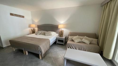 a hotel room with two beds and a couch at Studio Le Frangipanier au Gosier avec plage - location Prestige Caraïbes in Le Gosier