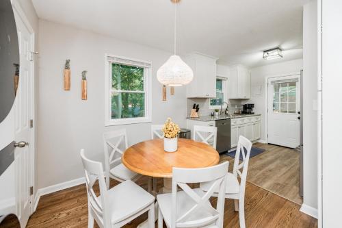a kitchen and dining room with a wooden table and white chairs at Hot Tub Fire Pit Oasis 3mi to Downtown in Raleigh