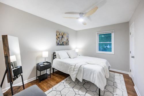 a white bedroom with a bed and a window at Hot Tub Fire Pit Oasis 3mi to Downtown in Raleigh