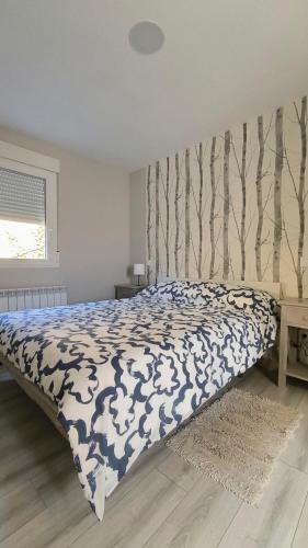 a bed with a blue and white comforter in a bedroom at Torreón El Guindal - Sierra de Gredos in Mijares