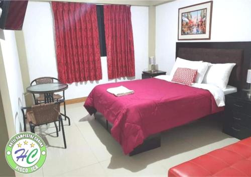 een slaapkamer met een bed met een rode deken en een tafel bij Pisco Hospedaje Corina in Pisco