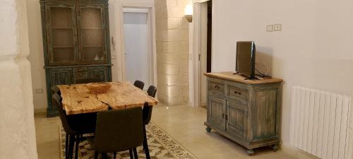 a dining room with a wooden table and a tv on a cabinet at Petrabianca di San Cesario di Lecce in San Cesario di Lecce