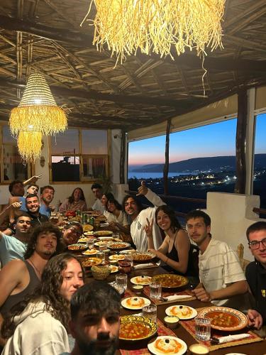 a group of people sitting around a long table with food at RED CARPET SURF CAMP - Traditional Moroccan GuestHouse With Stunning Views in Tamraght Ouzdar