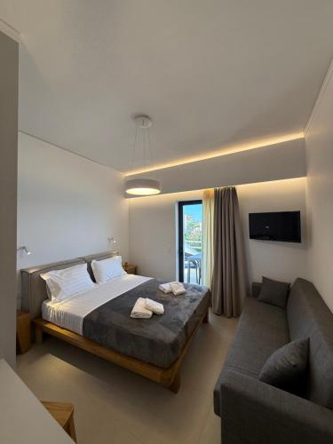a bedroom with a bed and a couch at Thalassa Luxury Apartments Nea Styra in Nea Stira