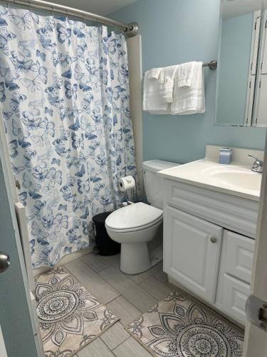 a bathroom with a toilet and a shower curtain at Panoramic Ocean View Condo in Galveston