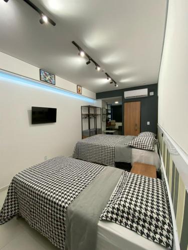 a room with two beds and a tv in it at Apartamento 107 Hotel Novo Centro in Petrolina