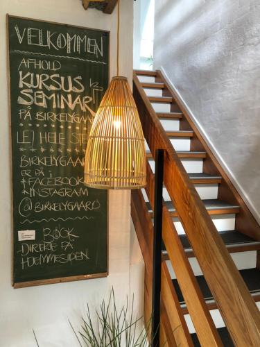 a lamp sitting next to a staircase with a chalkboard at Birkelygaard B&B in Millinge