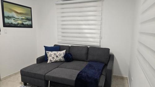 a living room with a gray couch with blue pillows at BioBay Suite Los Roires Beach Apartments in Fajardo
