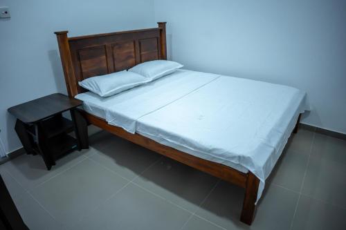 a bed with a wooden frame and a night stand next to it at Backpackers GuestHouse Trincomalee in Trincomalee