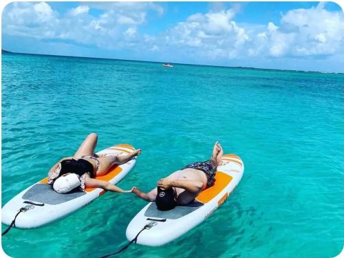 two people laying on surfboards in the water at BioBay Suite Los Roires Beach Apartments in Fajardo