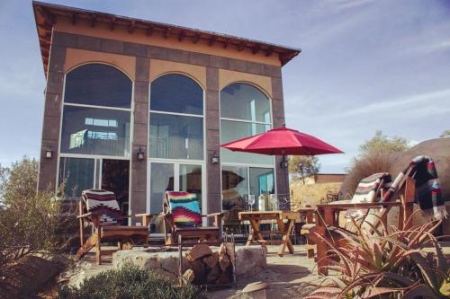 a building with chairs and an umbrella in front of it at En'kanto Valle de Guadalupe in San Marcos