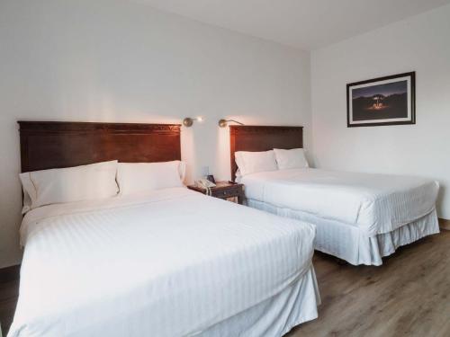 two beds in a hotel room with white sheets at HS HOTSSON Smart Value Tampico in Tampico