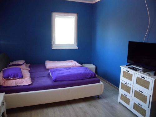 a bedroom with blue walls and a bed with purple pillows at Apartment in Siofok - Balaton 34933 in Balatonszabadi Fürdőtelep