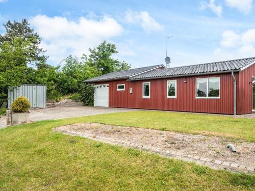 a red house with a garage and a yard at 6 person holiday home in Ebeltoft-By Traum in Ebeltoft