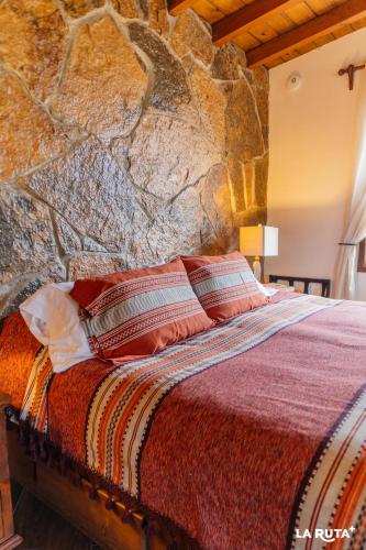 a bed in a room with a stone wall at En'kanto Valle de Guadalupe in San Marcos