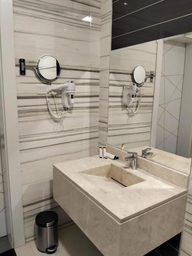 a bathroom with a sink and two mirrors at شقق كورال in Buraydah
