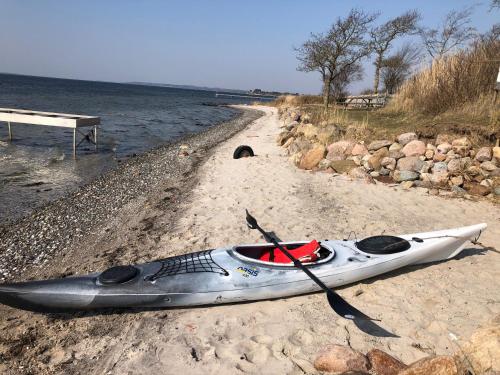 a kayak sitting on a beach next to the water at Birkelygaard B&B in Millinge