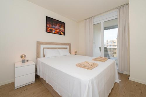 een witte slaapkamer met een wit bed en een raam bij 1 Bed Apartment Abedules Residence in El Campello