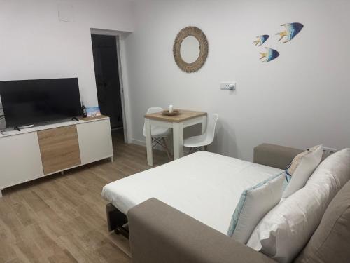 a living room with a couch and a tv and a table at Apartamento Bajo de Guía bajo A in Sanlúcar de Barrameda