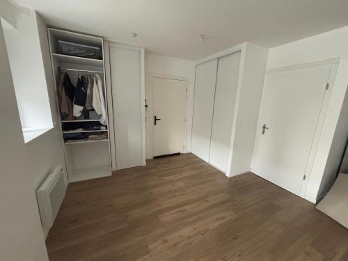 une pièce vide avec des armoires blanches et du parquet dans l'établissement Studio lumineux 45m2, à Annemasse