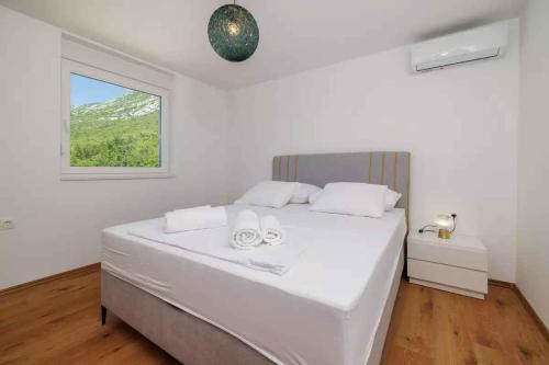 a white bedroom with a large bed with a window at Holiday home in Tribalj 51443 in Tribalj