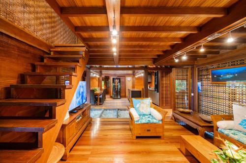 a living room with a large tv and wooden ceilings at Fare Makana in Maharepa