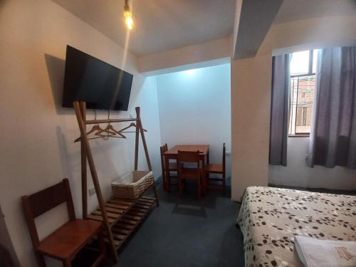 a room with a bed and a television and a table at Hospedaje Velilu in Ica