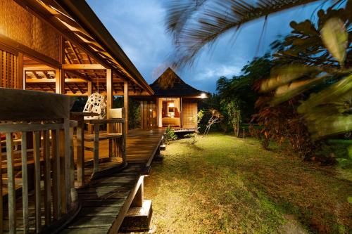 a house with a wooden porch and a yard at Fare Makana in Maharepa
