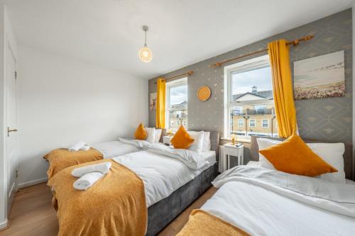 1 dormitorio con 3 camas con almohadas de color naranja en Dockside Home - 5 Comfy Beds-Perfect for Contractors and Families- Free Parking, en Londres