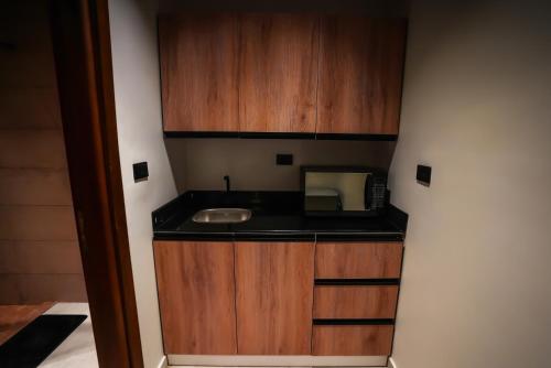 a small kitchen with a sink and wooden cabinets at Rivana Residence New Cairo - Pool Access in Cairo