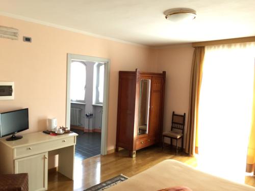 a living room with a bed and a desk with a television at Castelbourg in Neive