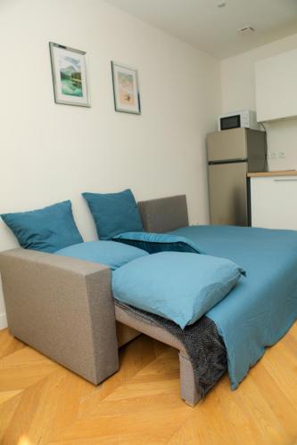 - un canapé dans le salon avec des oreillers bleus dans l'établissement Charme parisien idéal séjour à deux, à Aubervilliers